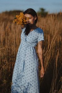 Portrait of young woman standing on field