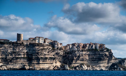 Buildings by sea against sky