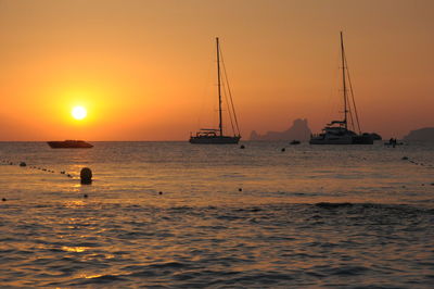 Silhouette sailboats in sea against sky during sunset