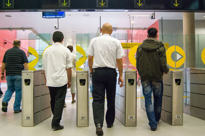 Rear view of people passing through the subway turnstiles