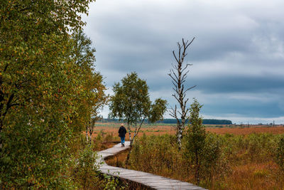 Woman walking on boardwalk against sky