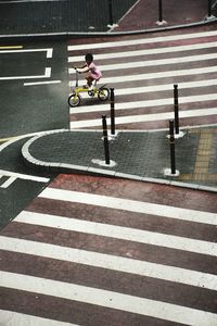 High angle view of girl on bicycle at zebra crossing in city