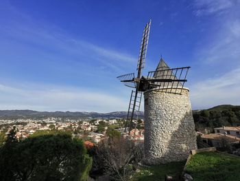 Traditional windmill on street amidst buildings against sky