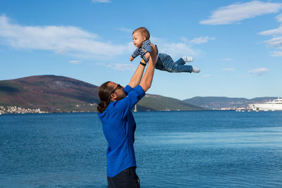 Father raises his son in his arms to the sea in montenegro