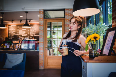 Woman standing by glass of building