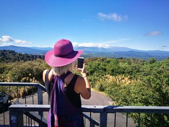 Rear view of woman standing by railing against mountain