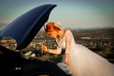 Side view of woman with umbrella in car