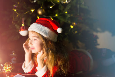 Portrait of young woman looking away at christmas tree