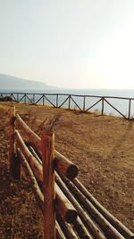 Wooden fence on field against clear sky