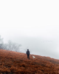 Rear view of man on field against sky
