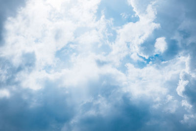 Low angle view of sunlight streaming through clouds