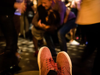 Low section of man wearing shoe with people in background at bar