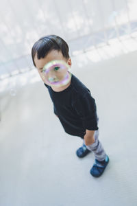 A boy looks through a soap bubble