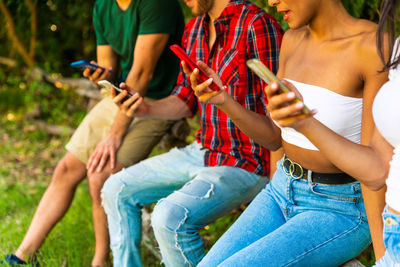 Rear view of people holding hands while sitting outdoors