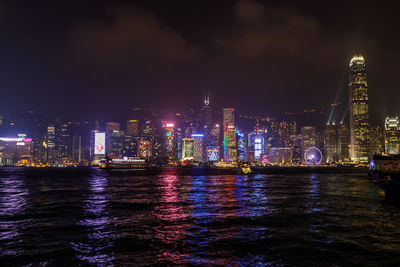 River by illuminated buildings against sky at night