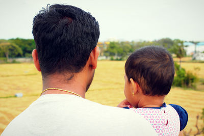 Rear view of father and son against sky