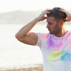 Mid adult man standing at beach against sky