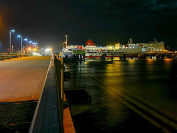 Illuminated harbor against sky at night