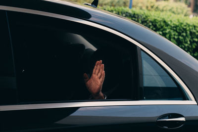 Cropped image of man waving hand in car