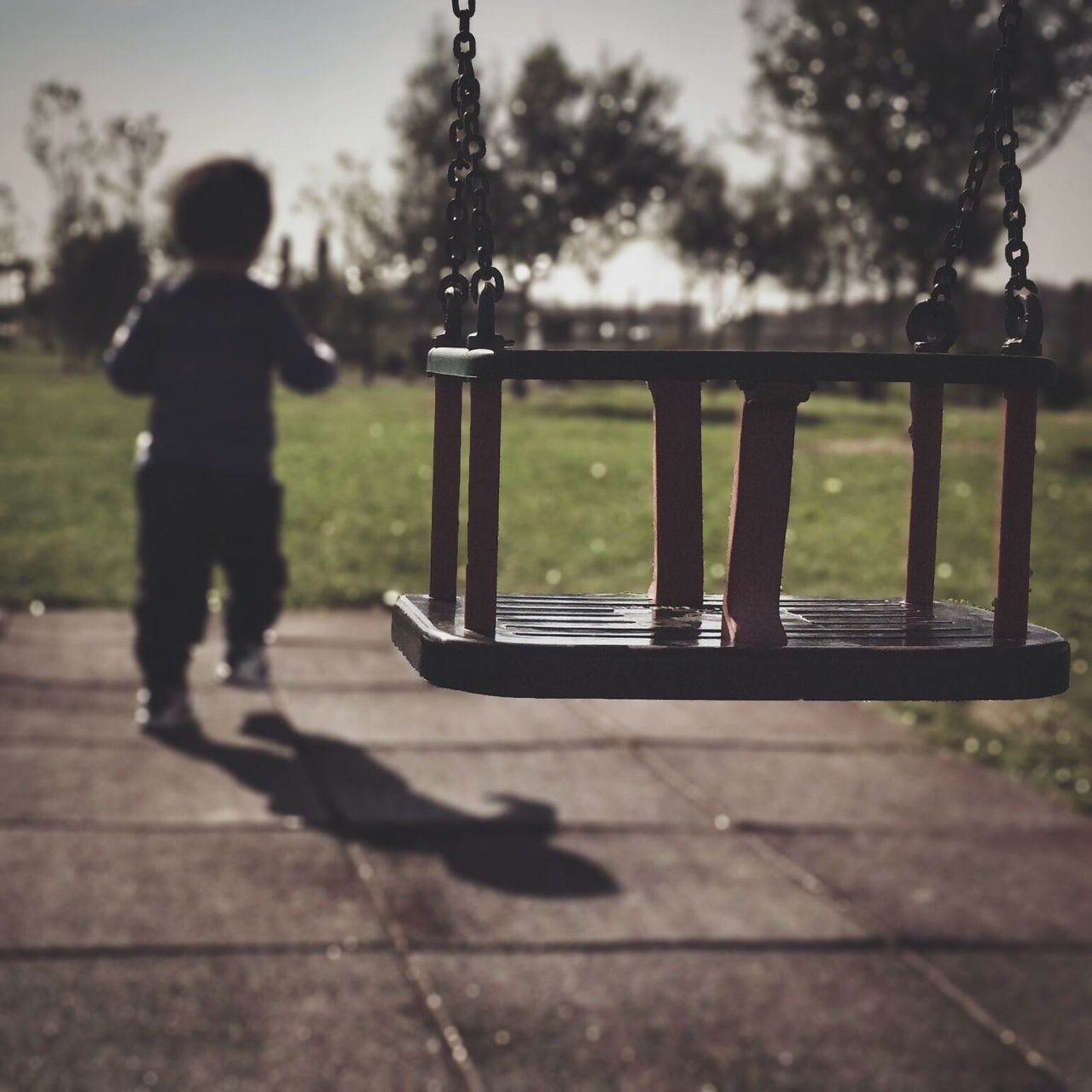 leisure activity, lifestyles, focus on foreground, sunlight, tree, childhood, shadow, rear view, men, railing, day, outdoors, bench, full length, silhouette, person, swing, sky