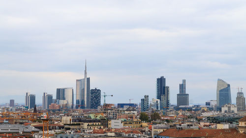 Buildings in city against cloudy sky