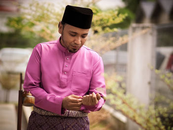 Man looking away while standing on pink outdoors