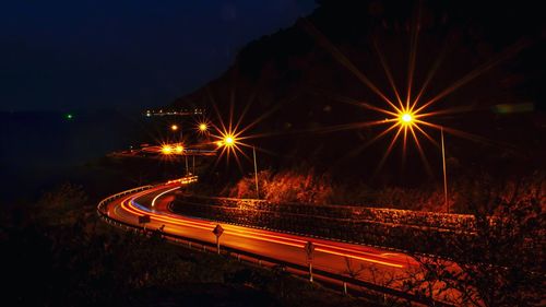 Light trails on road against sky at night