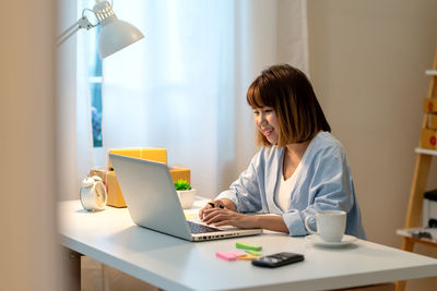 Rear view of woman using laptop on table