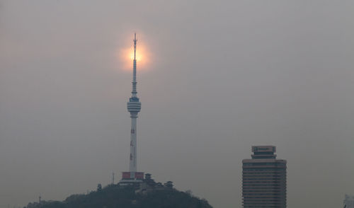 Communication tower against sky during sunset in city