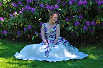 Girl in gown sitting against flowering plants