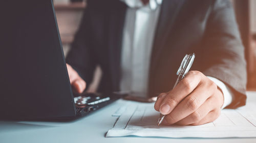 Midsection of man using laptop on table