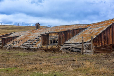 Abandoned wooden structure on field against sky