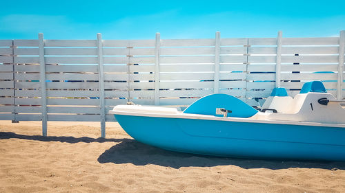 Boats moored on beach against blue sky