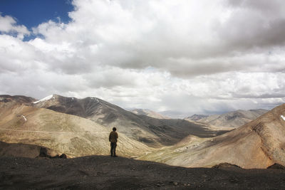 Woman on landscape against cloudy sky