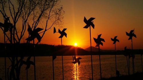 Silhouette birds flying over sea against sky during sunset