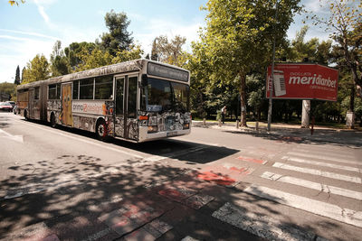 Road sign on street in city against sky