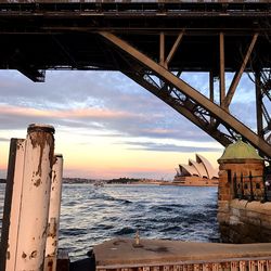 Silhouette bridge over sea against sky