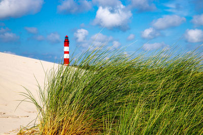 Lighthouse on beach against sky