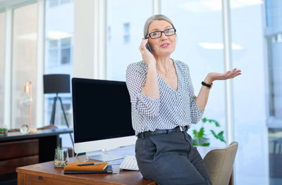 Side view of young woman using mobile phone while standing in office