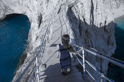 Rear view of woman standing on railing against sea