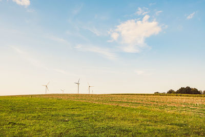 Wind turbines on field against sky