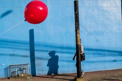 Rear view of man with balloons against blue sea