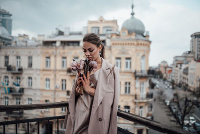 Young woman standing against buildings in city