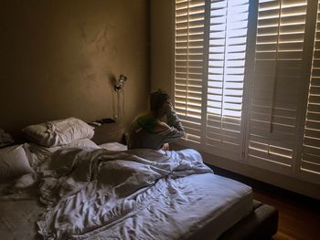 Teenage boy sitting on bed at home