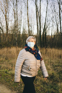 Senior woman with a face mask walking in nature