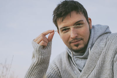 Portrait of man holding straw against sky during winter