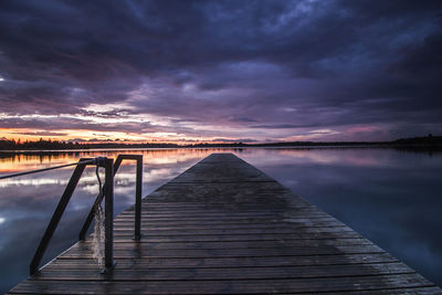 Pier over lake against cloudy sky during sunset