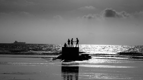 Silhouette people standing on beach against sky