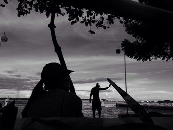 Silhouette people playing on beach against sky