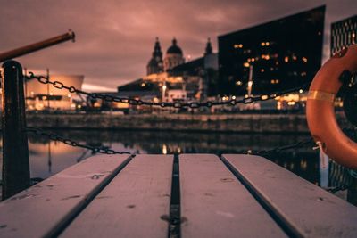 Bridge over river in city against sky during sunset